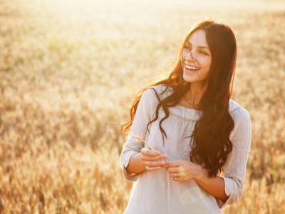 A woman happily laughing in a wheat field after individual counseling