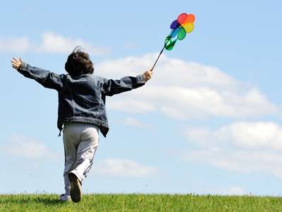 A happy child running on a grassy hill after seeing a child therapist online