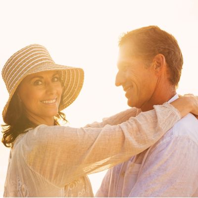 A man and woman hug in the afternoon sun smiling together after their online couples therapy