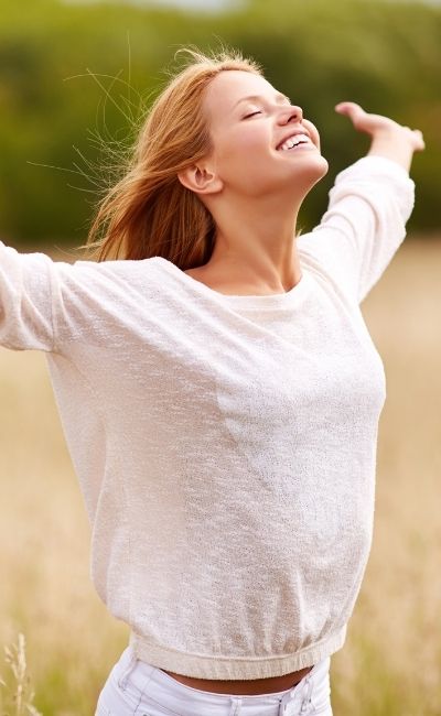 A woman smiling with arms out and raised feeling less anxiety after online therapy in Illinois with PRESENT Counseling in Chicago IL