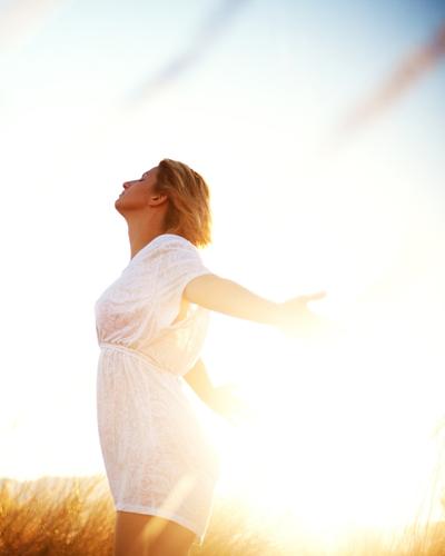 A woman smiling with arms out feeling less anxiety after online therapy in Illinois with PRESENT Counseling in Chicago IL